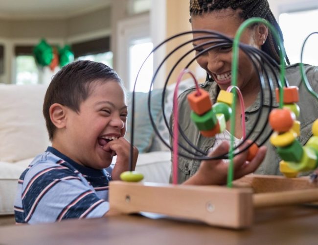 When the mid adult mom and her special needs son play in the living room, they laugh together.